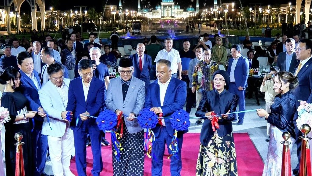 Para pejabat memotong pita pada soft opening HADITH Hotel di Samarkand, dengan Kompleks Imam Al-Bukhari yang terang di latar belakang.